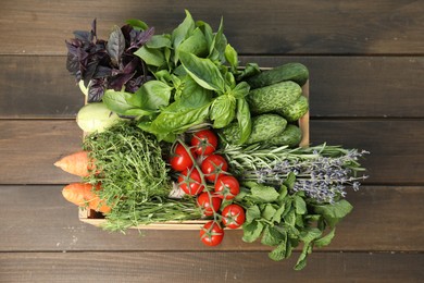 Different aromatic herbs and vegetables in crate on wooden table, top view