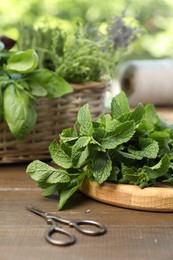 Photo of Mint with other aromatic herbs and scissors on wooden table, closeup