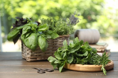 Different aromatic herbs and scissors on wooden table