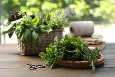 Different aromatic herbs and scissors on wooden table