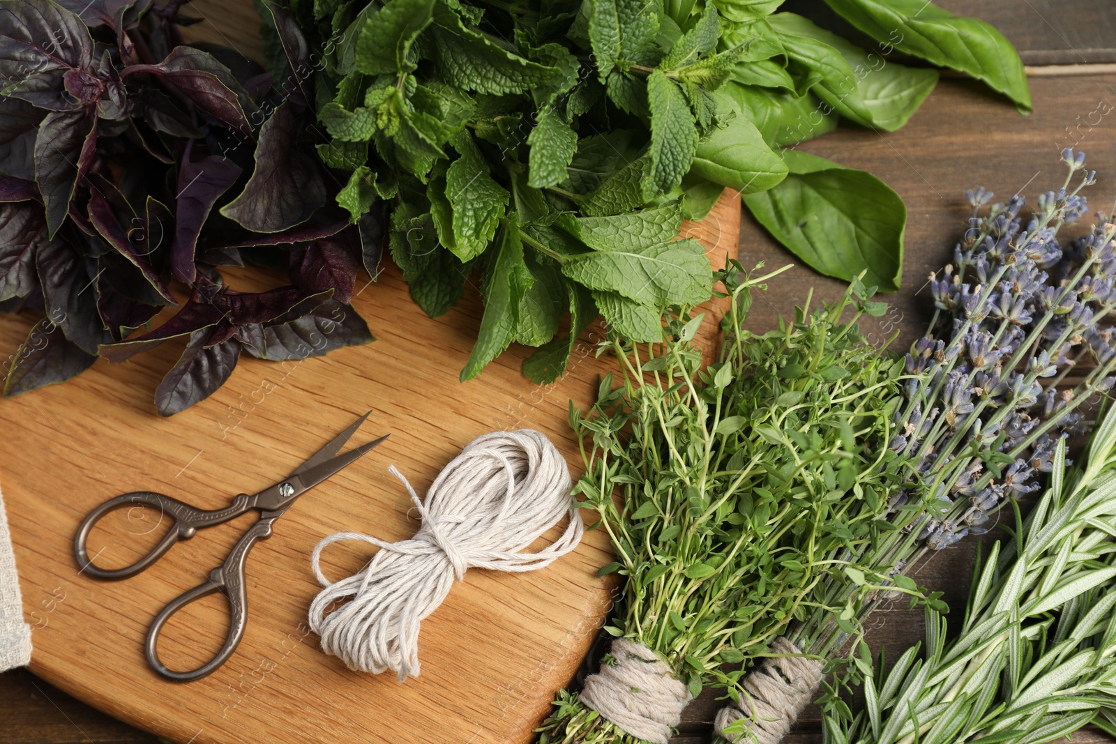 Photo of Different aromatic herbs, thread and scissors on wooden table, above view