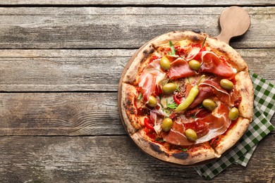 Photo of Tasty pizza with cured ham, olives, sun-dried tomato and pepper on wooden table, top view. Space for text