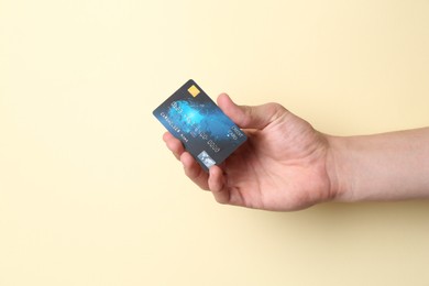 Photo of Man holding credit card on pale yellow background, closeup