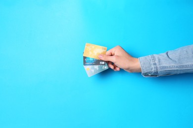 Photo of Man holding credit cards on light blue background, closeup