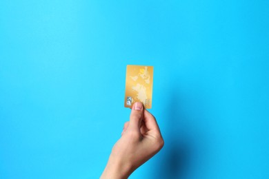 Photo of Man holding credit card on light blue background, closeup