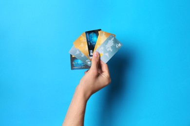 Photo of Man holding credit cards on light blue background, closeup