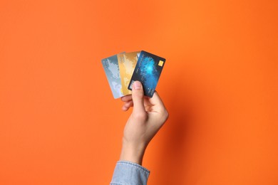 Photo of Man holding credit cards on orange background, closeup