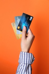 Photo of Woman holding credit cards on orange background, closeup