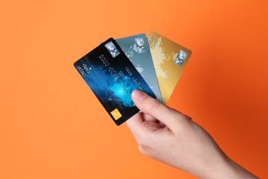 Photo of Woman holding credit cards on orange background, closeup