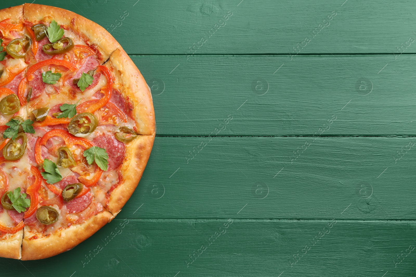 Photo of Delicious pizza Diablo on green wooden table, top view. Space for text