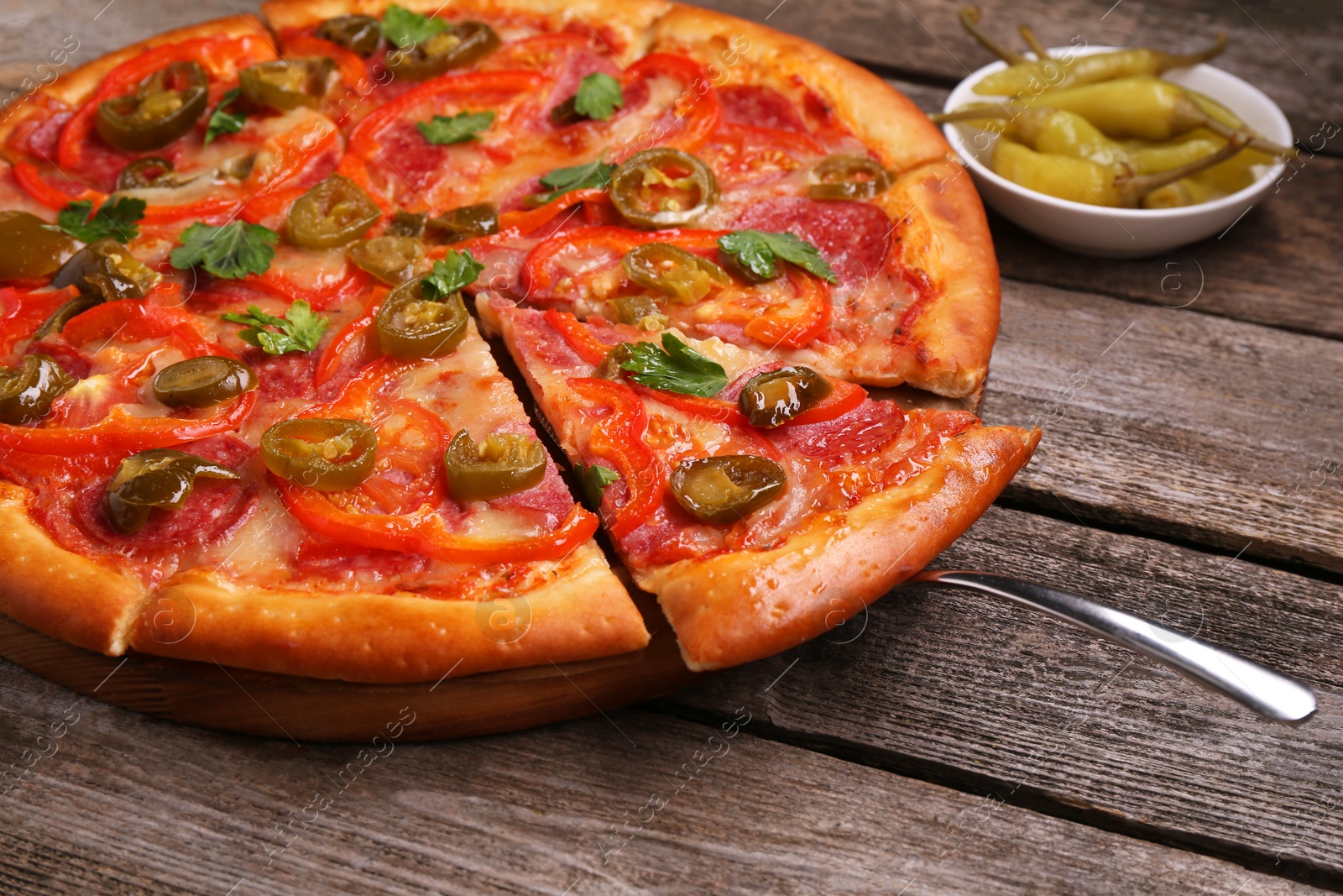 Photo of Delicious pizza Diablo and pickled peppers on wooden table, closeup