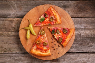 Photo of Pieces of delicious pizza Diablo, pickled peppers and spices on wooden table, top view