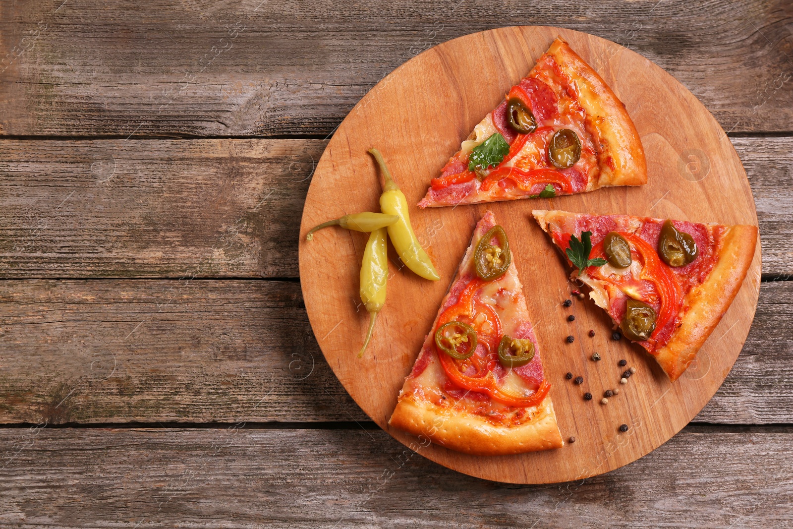 Photo of Pieces of delicious pizza Diablo, pickled peppers and spices on wooden table, top view. Space for text