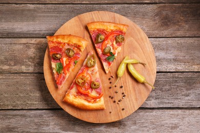 Photo of Pieces of delicious pizza Diablo, pickled peppers and spices on wooden table, top view