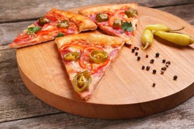 Photo of Pieces of delicious pizza Diablo, pickled peppers and spices on wooden table, closeup