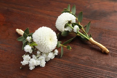 Photo of Two small stylish boutonnieres on wooden table