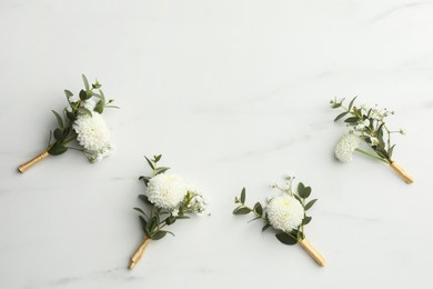 Photo of Small stylish boutonnieres on white marble table, flat lay. Space for text