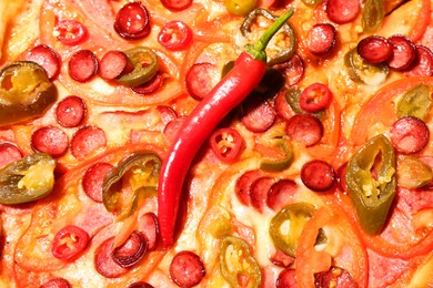 Delicious pizza Diablo with chili pepper as background, top view