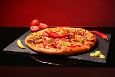 Delicious pizza Diablo and peppers on slate board against red background