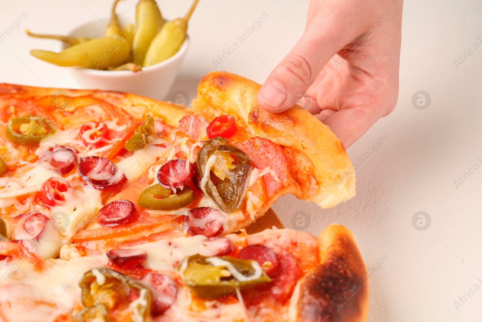 Photo of Woman taking piece of delicious pizza Diablo at white textured table, closeup