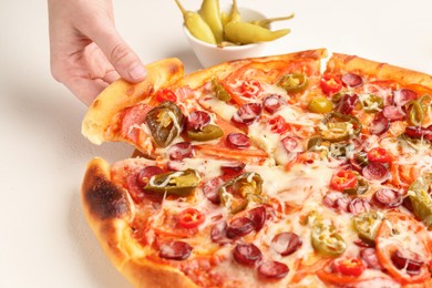 Photo of Woman taking piece of delicious pizza Diablo at white textured table, closeup