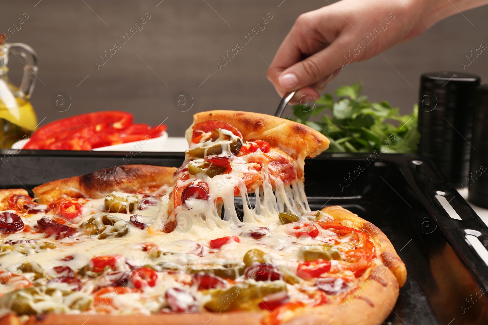 Photo of Woman taking piece of delicious pizza Diablo from baking tray, closeup