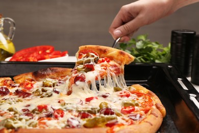 Photo of Woman taking piece of delicious pizza Diablo from baking tray, closeup