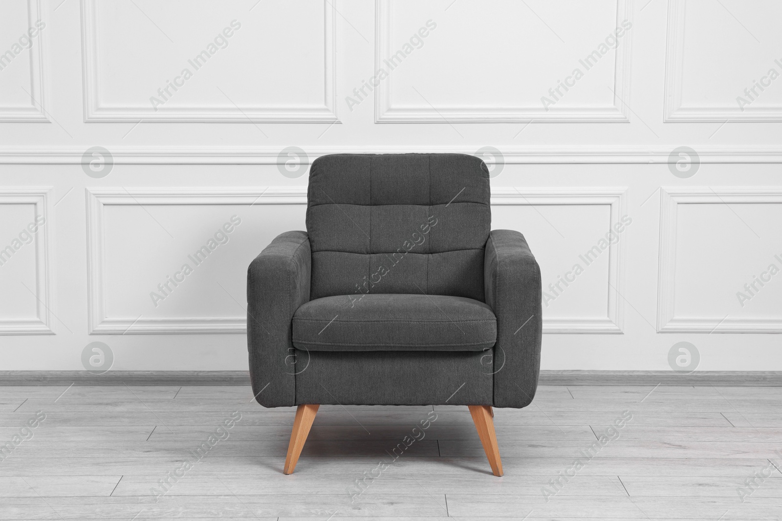 Photo of One soft armchair near white wall indoors