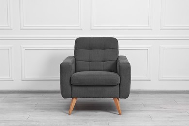 One soft armchair near white wall indoors