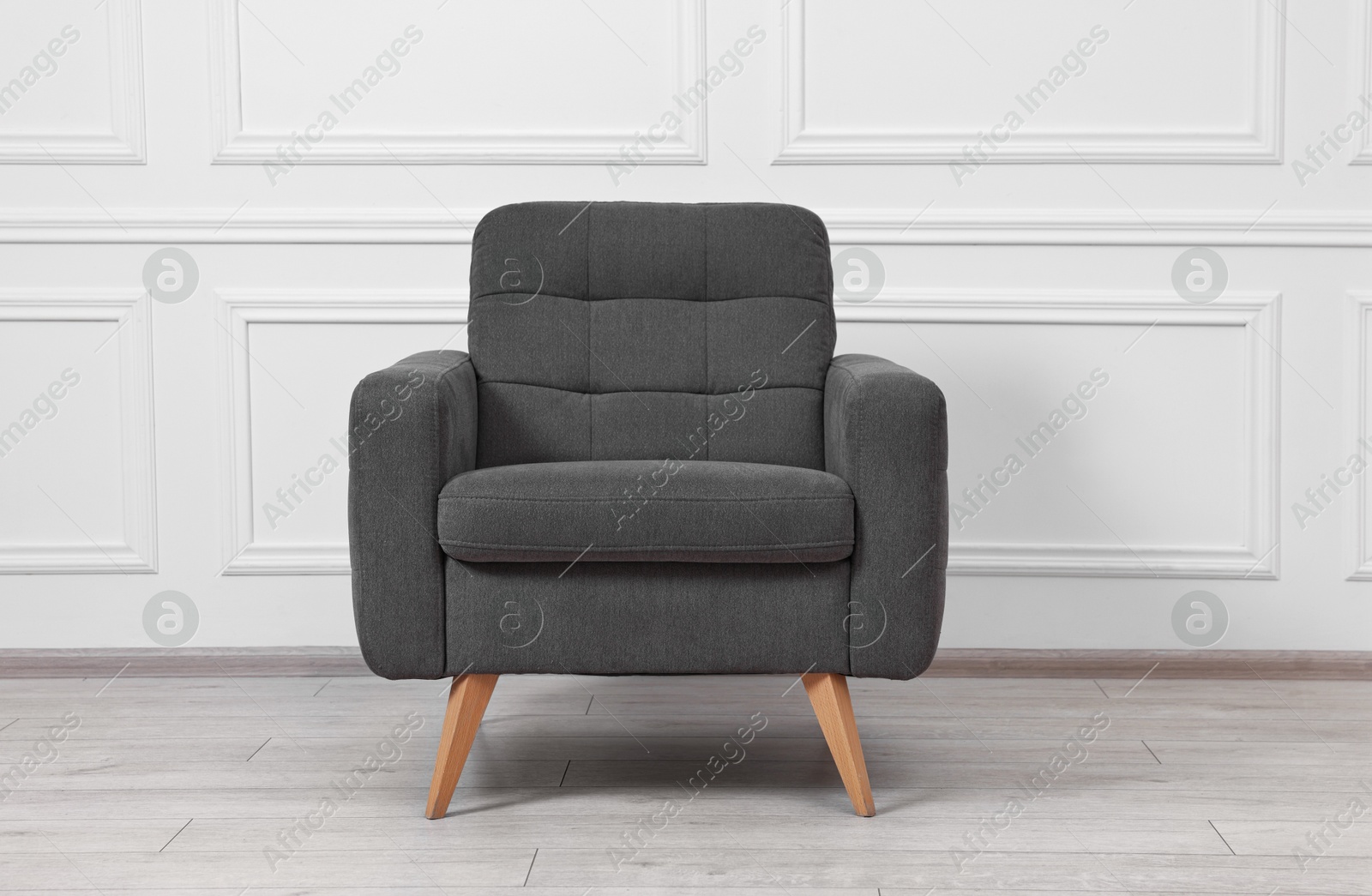 Photo of One soft armchair near white wall indoors