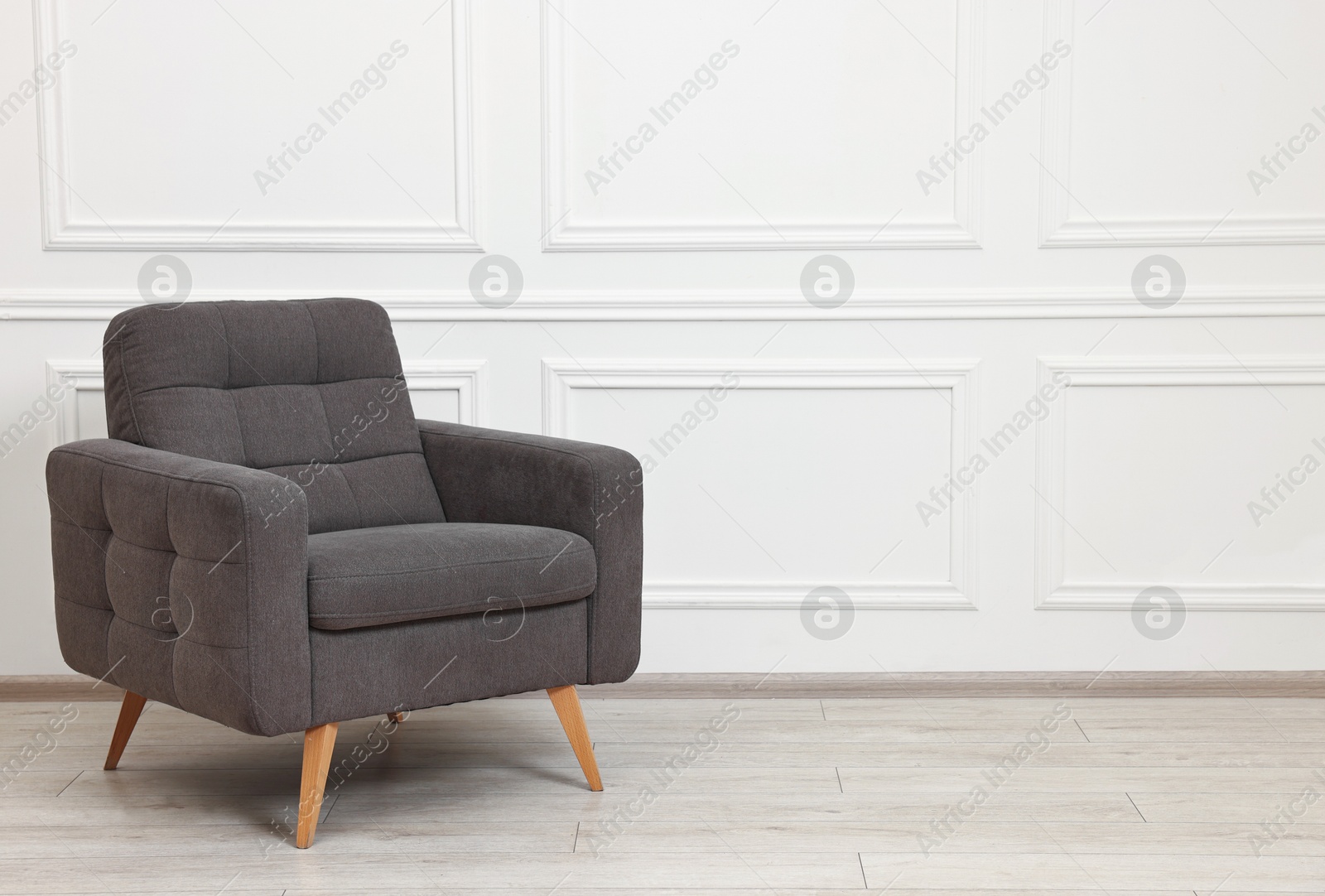 Photo of One soft armchair near white wall indoors. Space for text