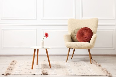 Photo of Soft armchair and coffee table with flower in stylish room