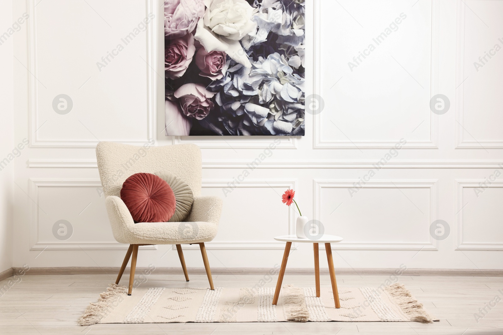 Photo of Soft armchair, coffee table with flower and picture in stylish room