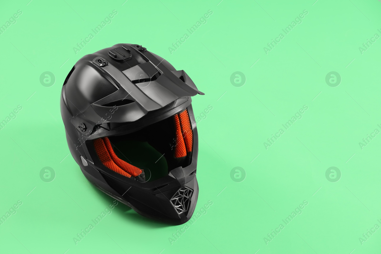 Photo of Modern motorcycle helmet with visor on light green background. Space for text