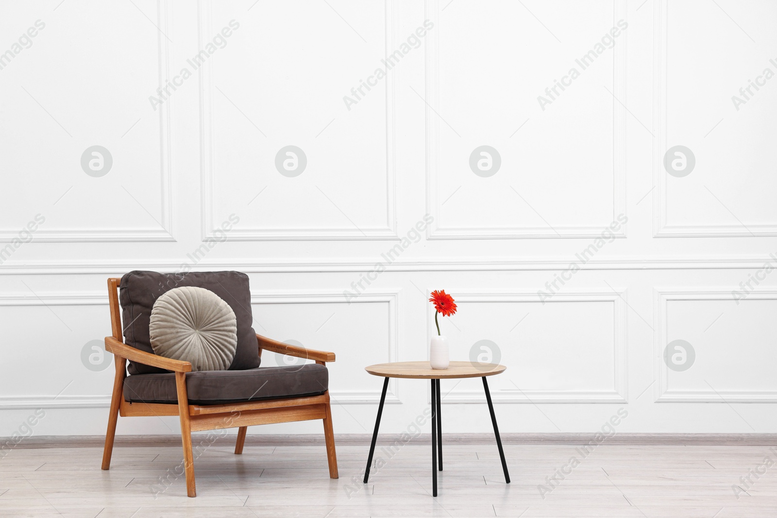 Photo of Comfortable armchair with pillow and coffee table near white wall, space for text. Interior design