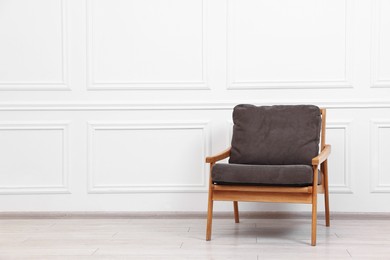 Photo of Comfortable soft armchair near white wall, space for text