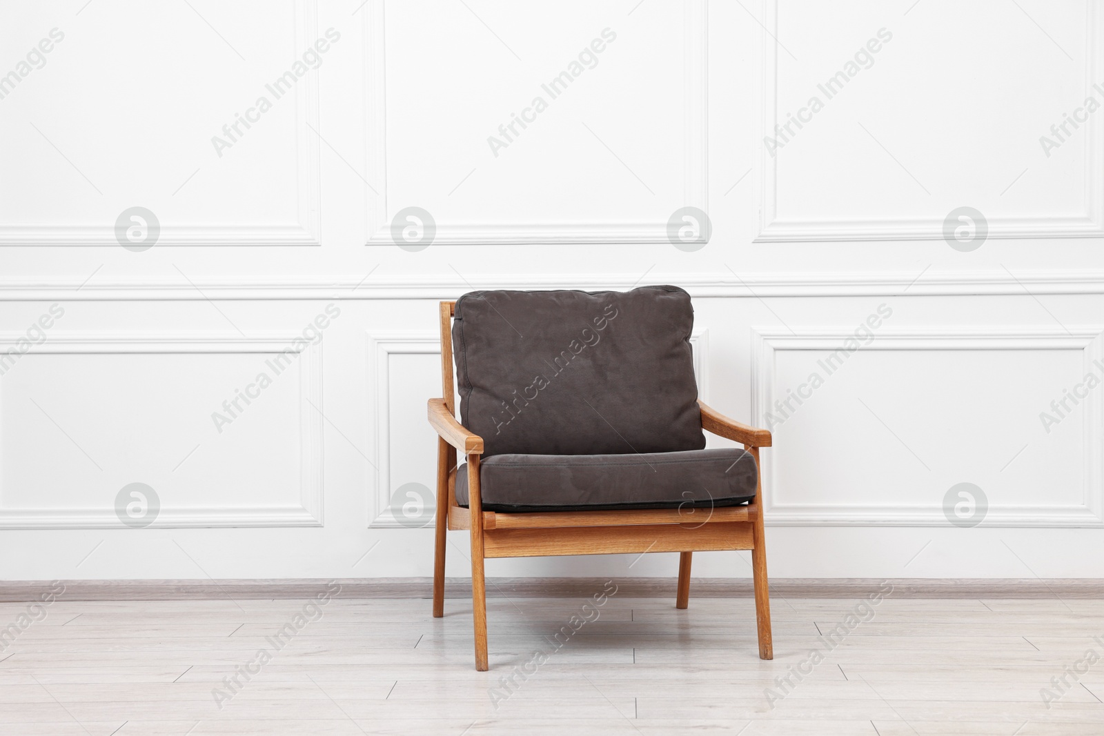 Photo of One comfortable soft armchair near white wall