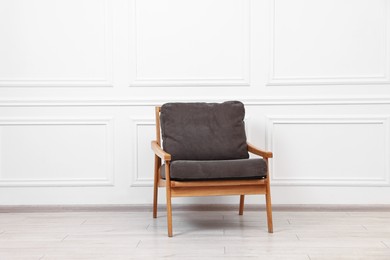 Photo of One comfortable soft armchair near white wall