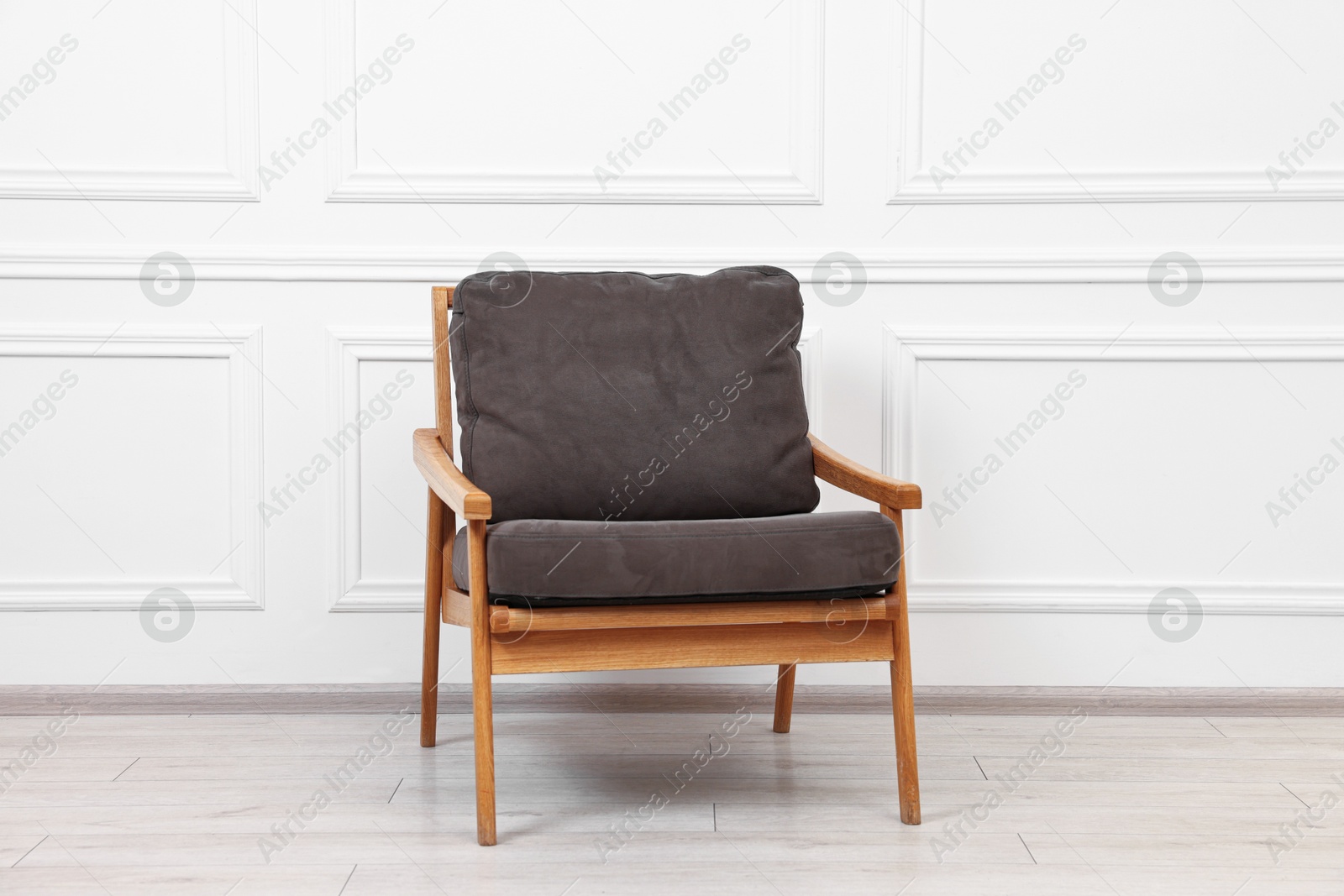 Photo of One comfortable soft armchair near white wall