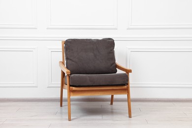 Photo of One comfortable soft armchair near white wall