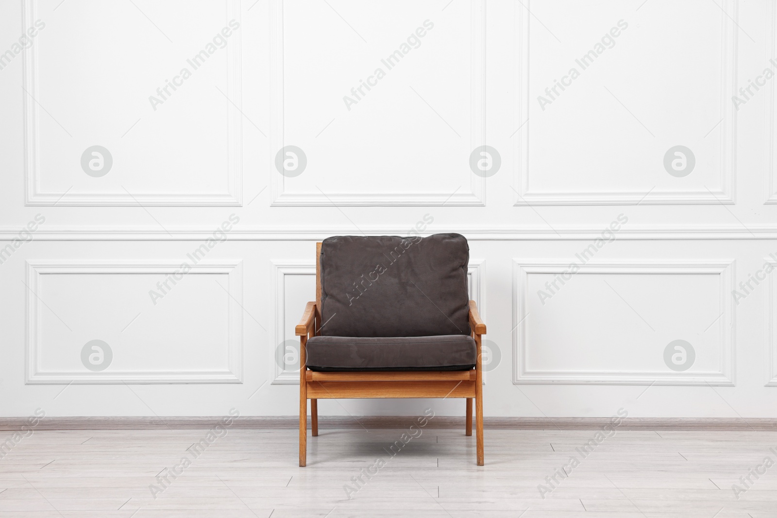 Photo of One comfortable soft armchair near white wall