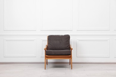 One comfortable soft armchair near white wall