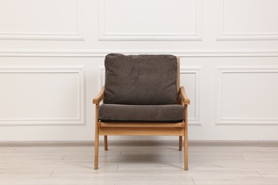 Photo of One comfortable soft armchair near white wall