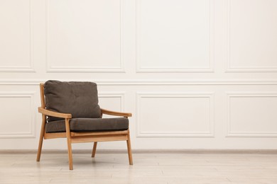 Photo of Comfortable soft armchair near white wall, space for text