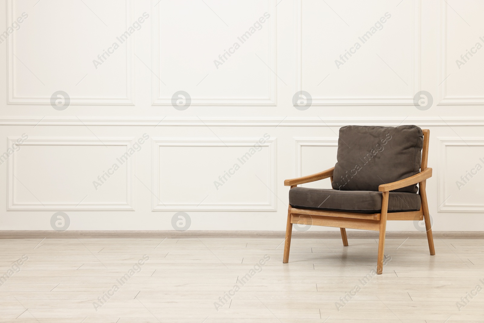 Photo of Comfortable soft armchair near white wall, space for text