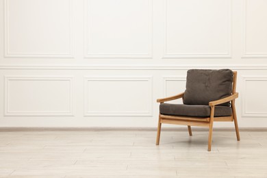 Photo of Comfortable soft armchair near white wall, space for text