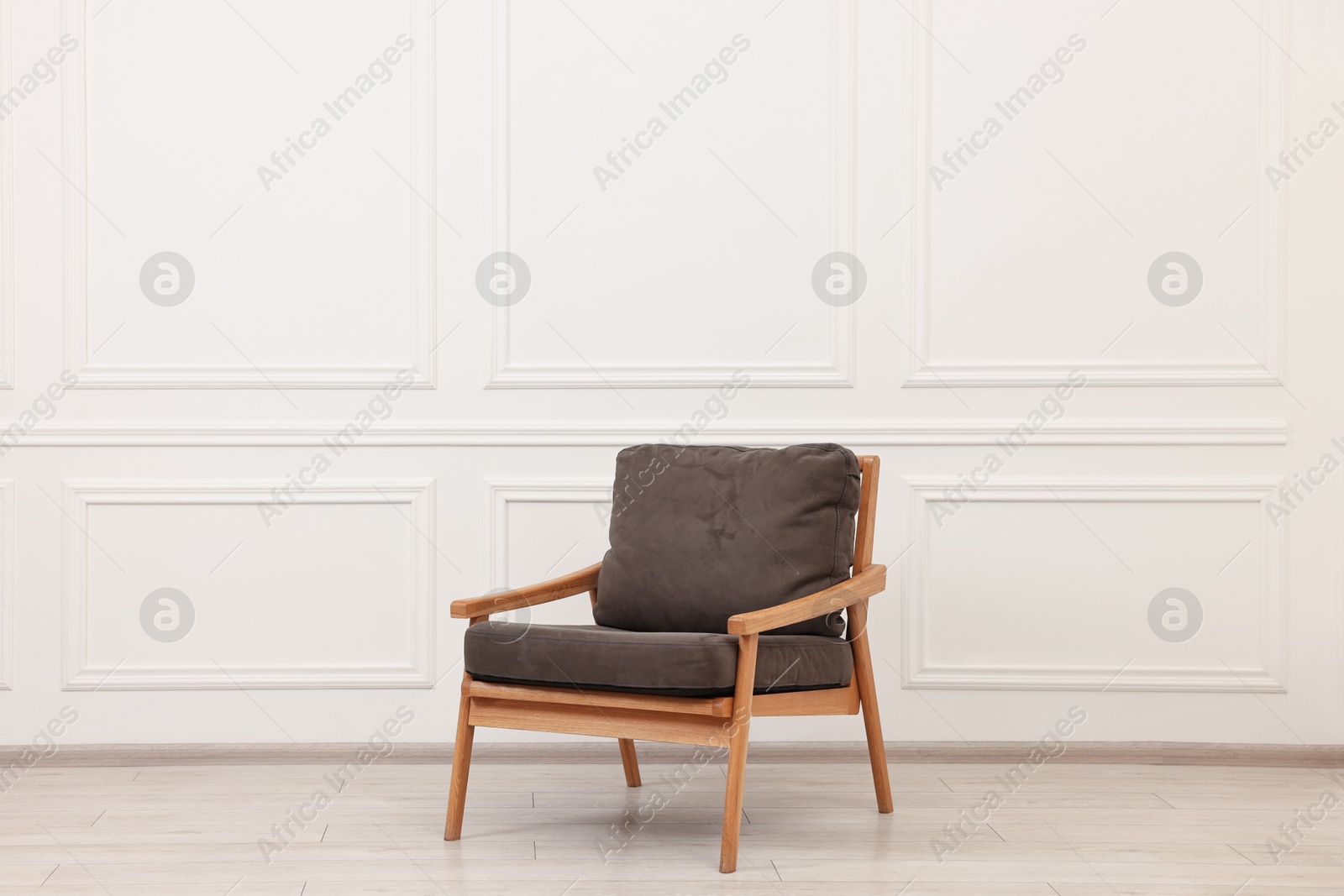 Photo of One comfortable soft armchair near white wall