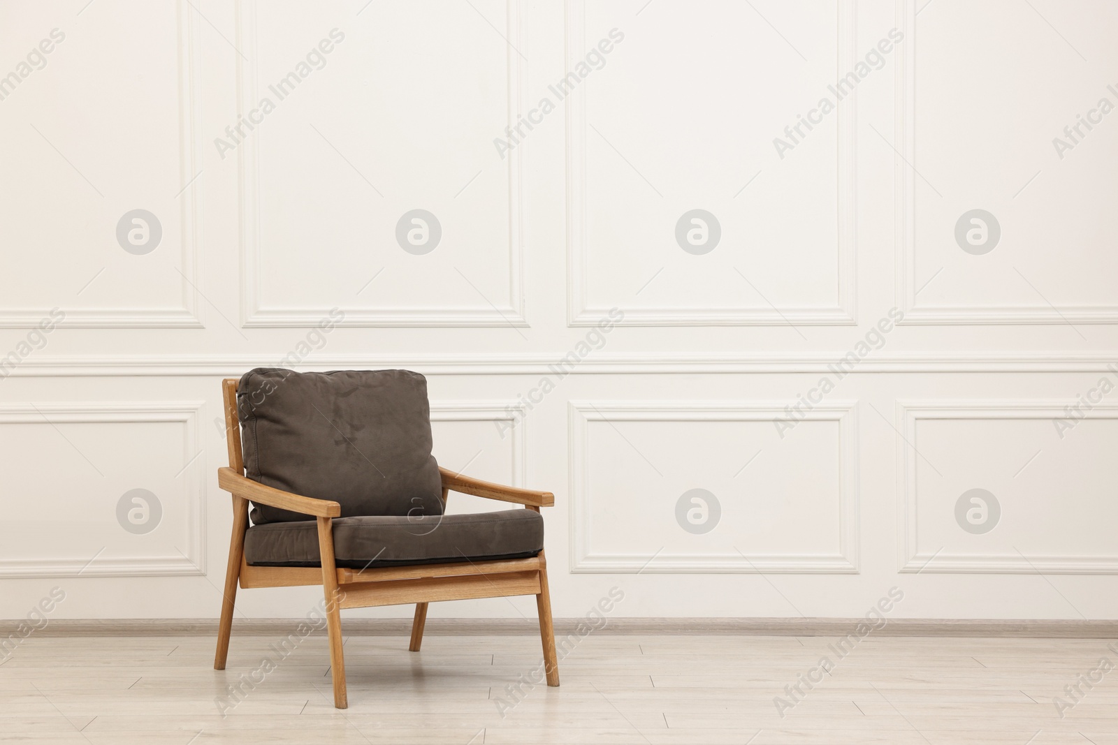 Photo of Comfortable soft armchair near white wall, space for text