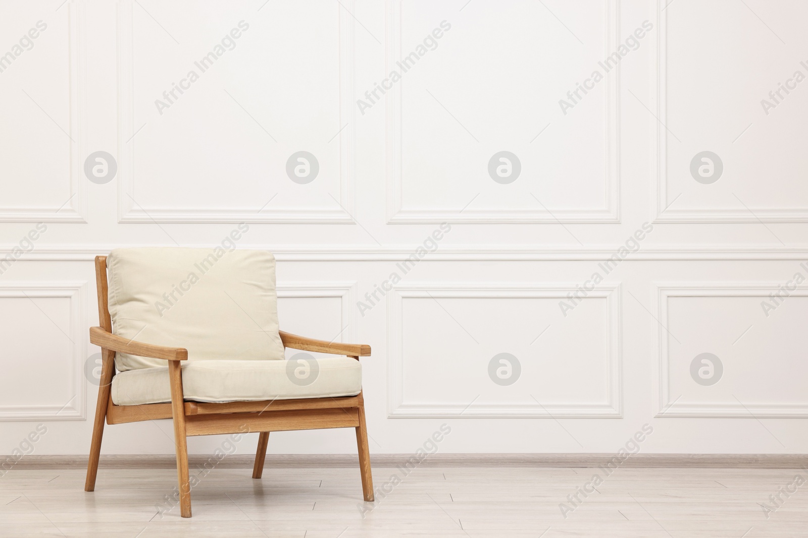 Photo of Comfortable soft armchair near white wall, space for text