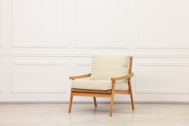 One comfortable soft armchair near white wall